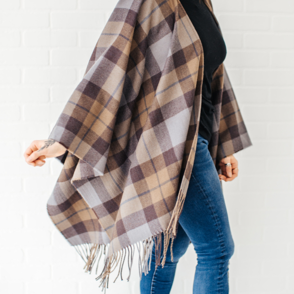 A woman wearing a plaid OUTLANDER Wrap Premium Lambswool Tartan and jeans.