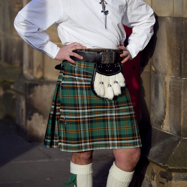 A man in a kilt posing for a picture.