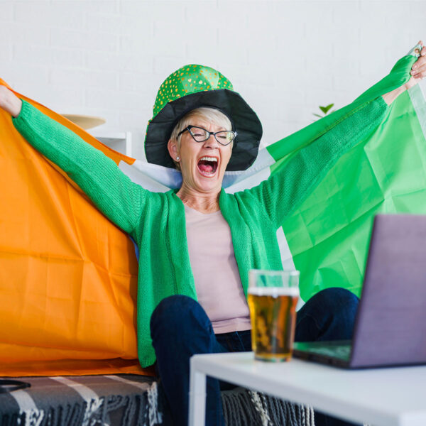 A woman sitting on a couch with a laptop and irish flag.
